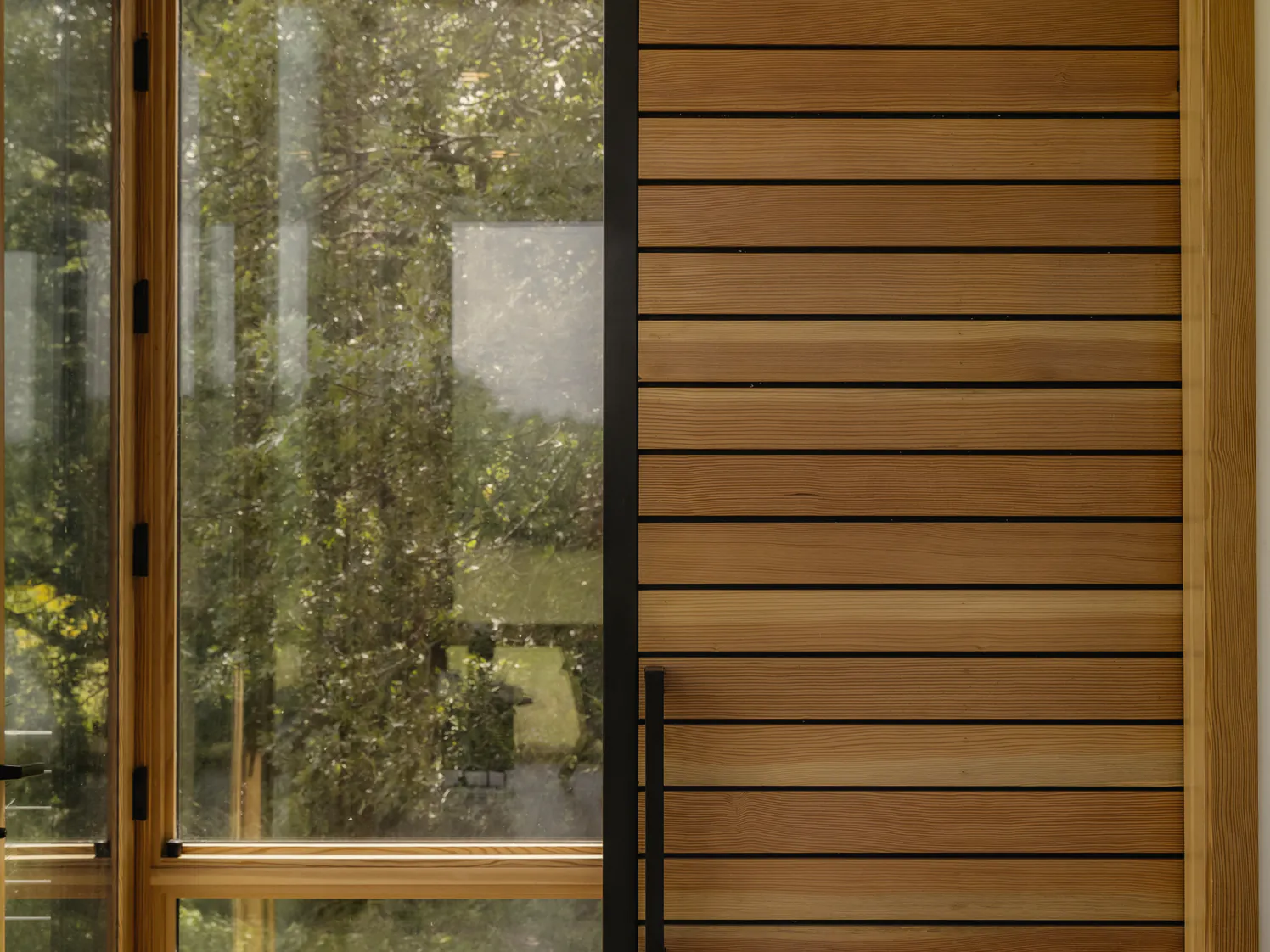 The glass door and the timber slat door to the shower room, with trees outside