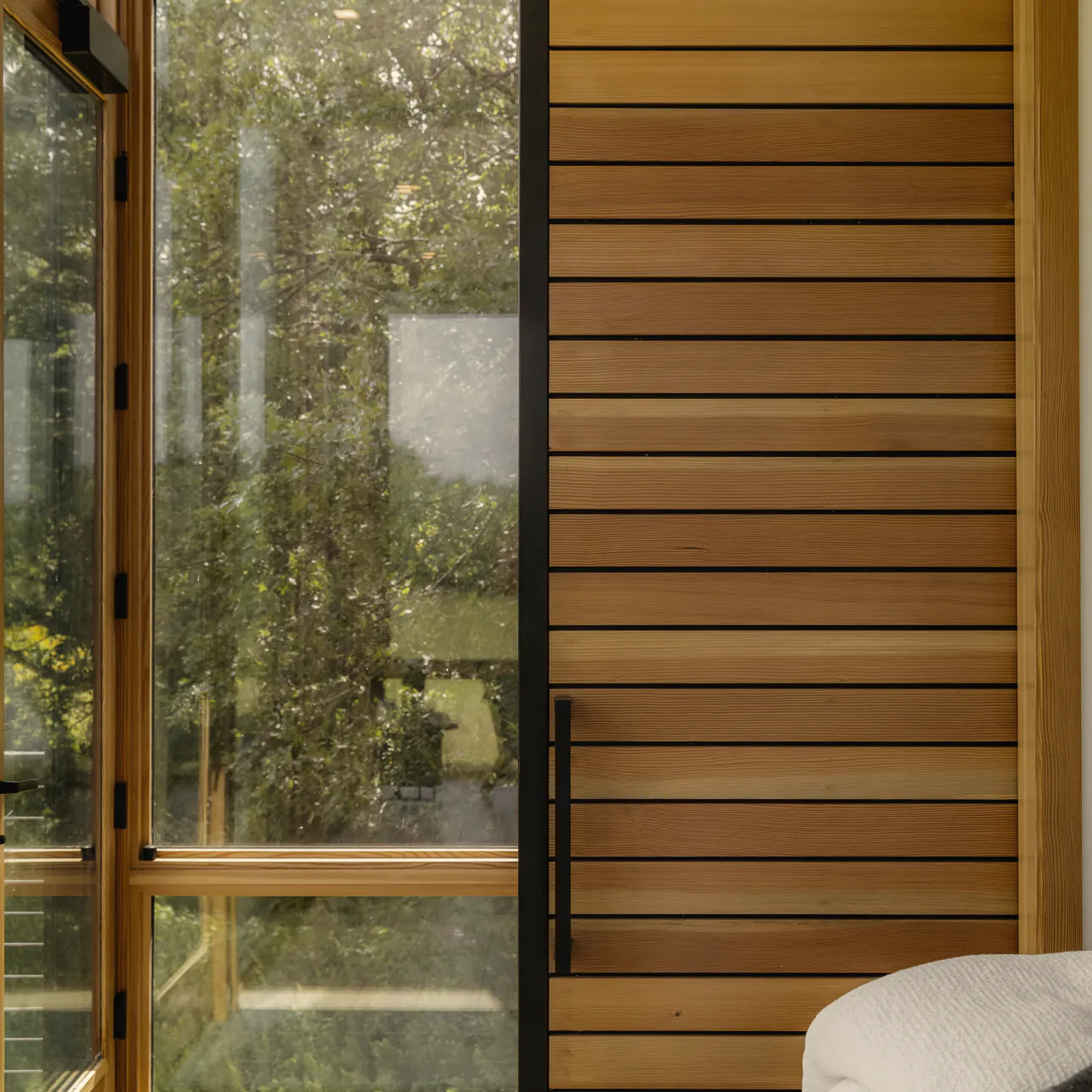 The glass door and the timber slat door to the shower room, with trees outside