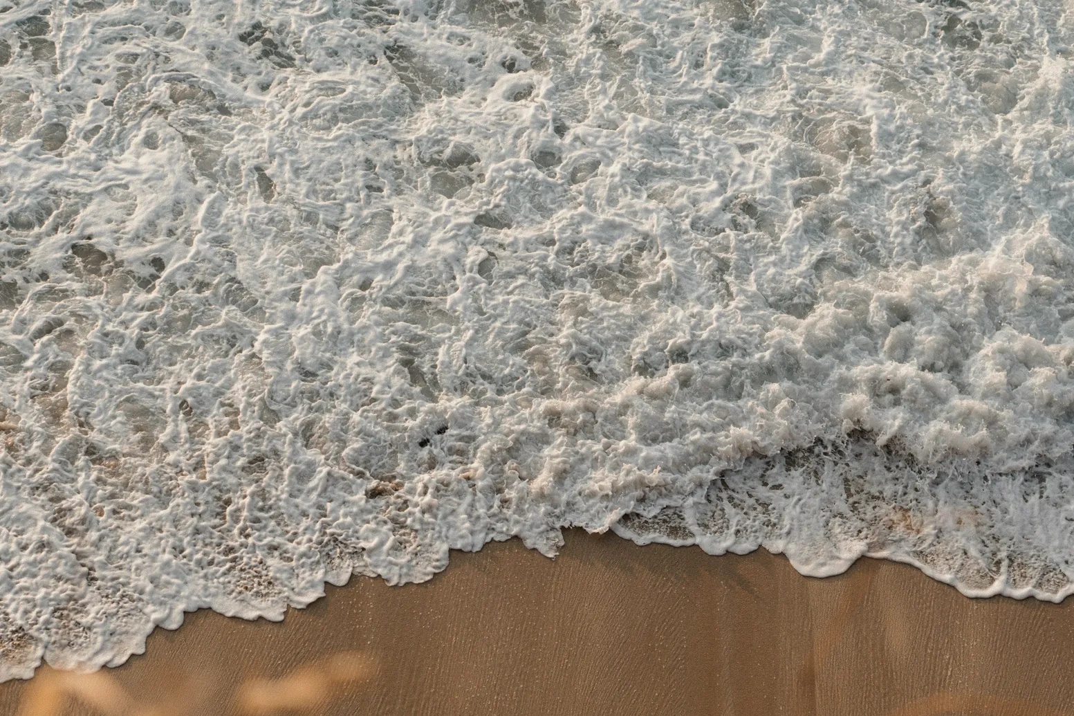 The beach below the room from above, foam running in over the sand