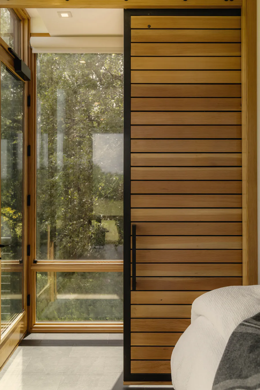 The glass door and the timber slat door to the shower room, with trees outside